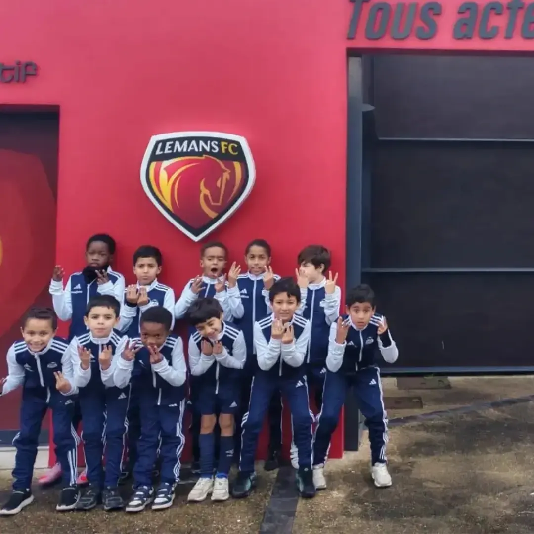 Les U9 et U10 du VFA en survêtement devant le mur rouge du Mans FC