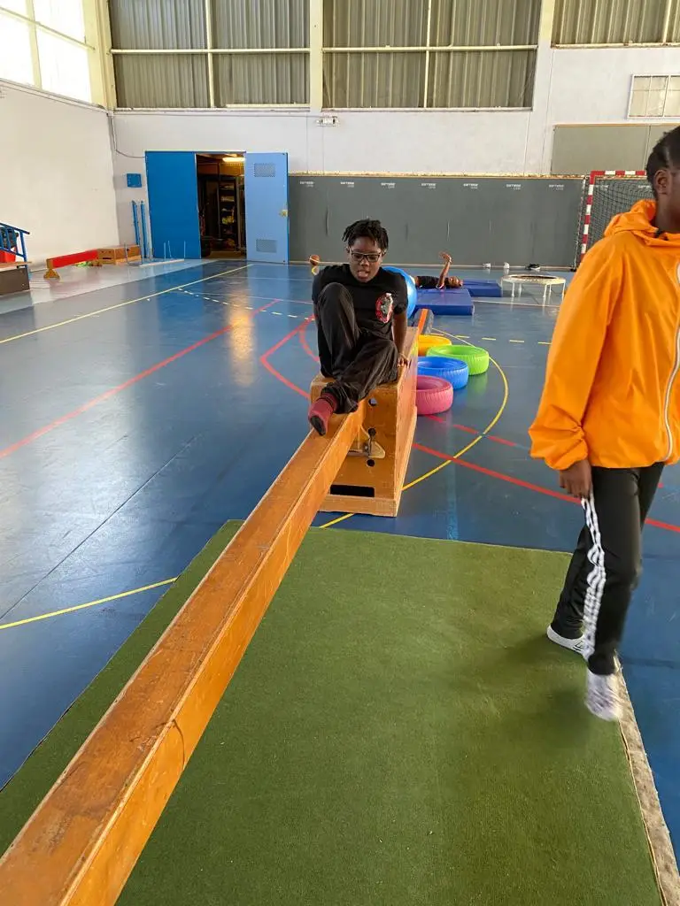 Un jeune avance sur une poutre d’équilibre, accompagné d’un encadrant